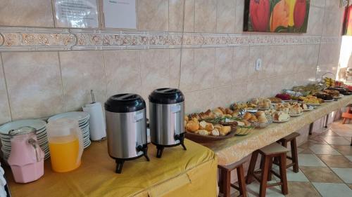 a table with a buffet of food and orange juice at Hotel Pousada Recanto da Madá in Aparecida