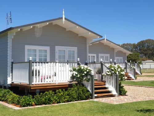 a house with a porch and a white fence at Dangerfield Oaks Boutique Cottage's in Mudgee