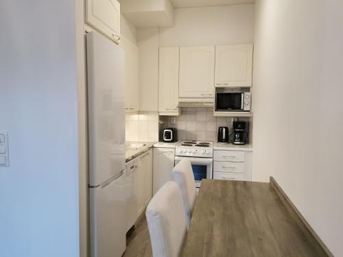 a kitchen with a wooden table and white appliances at Rovaniemi Cityhome Sunnarborg in Rovaniemi