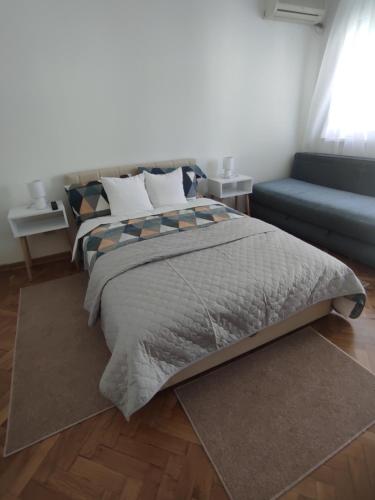 ein Schlafzimmer mit einem Bett und einem blauen Sofa in der Unterkunft Apartman Nicolas in Karaburma