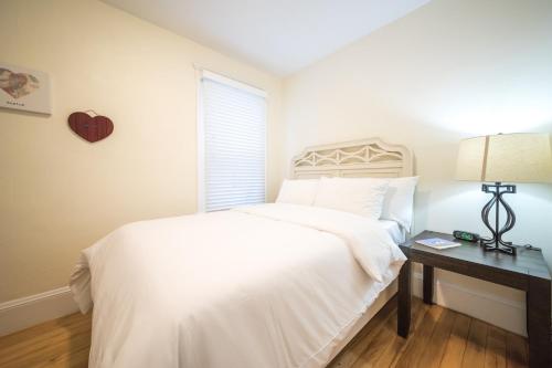 a bedroom with a white bed and a window at The Boston Rental - Multiple Floorplans in Boston