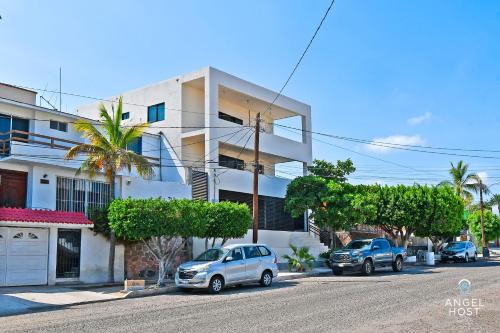 dos autos estacionados en una calle frente a un edificio en NEW Comfy Stay with Pool Onsite Steps from Malecón en La Paz