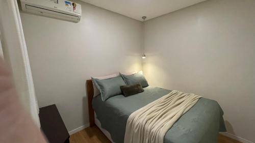um pequeno quarto com uma cama e um aquecedor em Apto climatizado 3 quartos a 3,7km da Vila Germânica em Blumenau