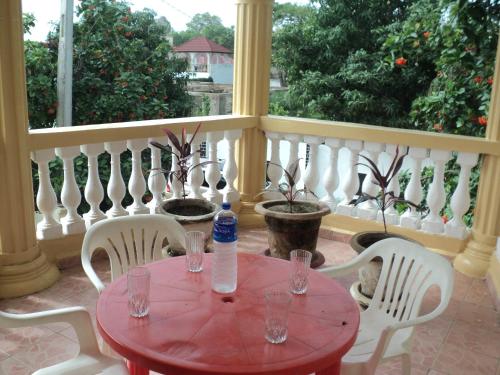 a red table and chairs on a balcony at Fayes Apartments in Brusubi