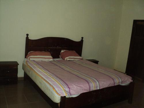 a bed with two pillows on it in a bedroom at Fayes Apartments in Brusubi