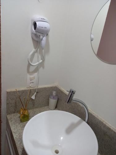 a bathroom with a white sink and a hair dryer at Requinte, conforto e privacidade in Pirenópolis