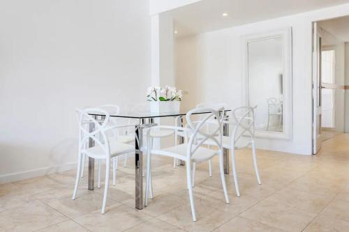 a dining room with a glass table and white chairs at Lujoso y Equipado Apartamento en Playa del Arenal in Jávea