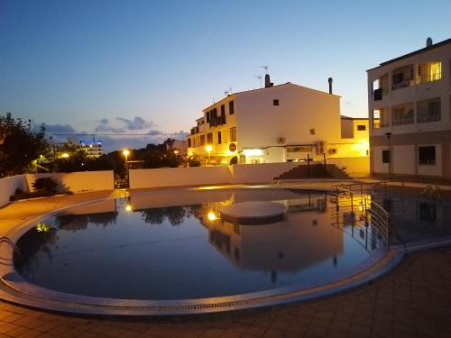 Apartamentos Calan Blanes Park, CB, APM 2142 في كالا إن بلانيس: مسبح في الليل مع مباني في الخلف