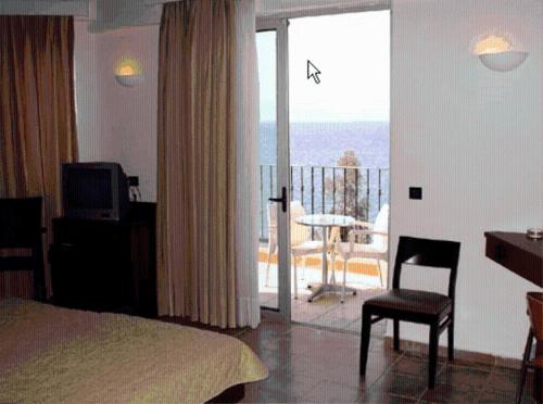 1 dormitorio con cama, escritorio y balcón en Thalassa, en Loutra Edipsou