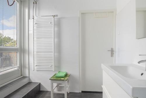 a white bathroom with a sink and a stool at Appartement De Boppeslach in Marssum