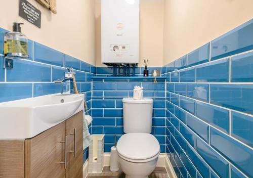 a blue tiled bathroom with a toilet and a sink at The Sun Deck in Aldeburgh