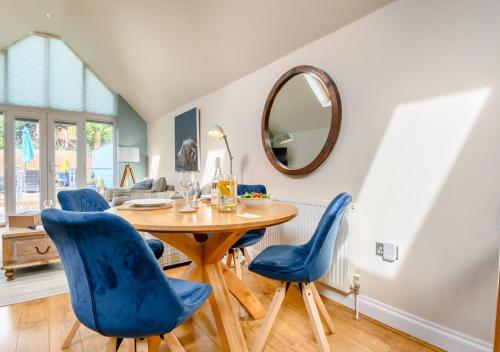 a dining room with a wooden table and blue chairs at The Sun Deck in Aldeburgh