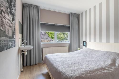Appartement De Boppeslach في Marssum: غرفة نوم بسرير ومغسلة ونافذة