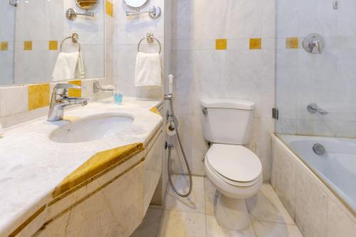a bathroom with a toilet and a sink and a tub at Montana Al Azizia Hotel in Makkah
