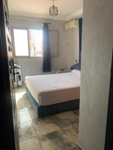 a bedroom with a bed with blue curtains and a window at Familiale Chambre calm wifi Hanae in Marrakech