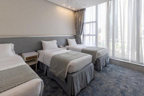 a hotel room with three beds and a window at Montana Al Azizia Hotel in Makkah