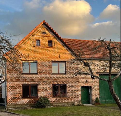 a brick house with a green door and a tree at Landdomizil Zeißig in Hoyerswerda