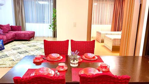 a living room with a table and red chairs at Хайвилл Астана in Astana