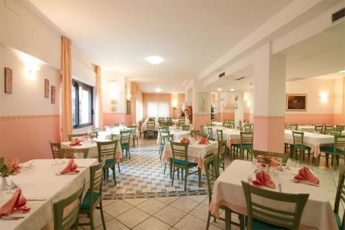 une salle à manger avec des tables et des chaises blanches dans l'établissement Hotel San Francesco, à San Giovanni Rotondo