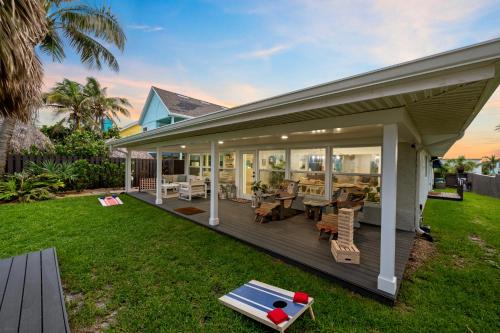 a house with a large deck with chairs and tables at Oceanfront Cocoa Beach Vacation Home Private Beach, Tiki Bar & Family Fun in Cocoa Beach