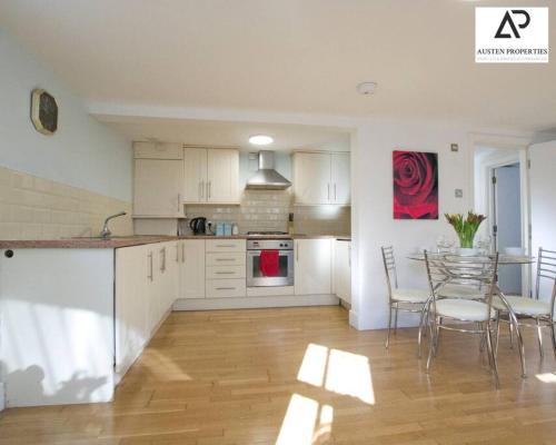 a kitchen with white cabinets and a table and chairs at 2 Bedroom Flat - Free Parking - Close to Beach in Portsmouth