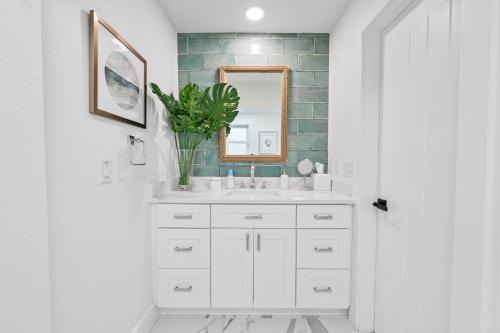 La salle de bains est pourvue d'un lavabo blanc et d'un miroir. dans l'établissement Vista Del Mar Oceanfront Home Stunning Views Backyard Oasis, à Cocoa Beach