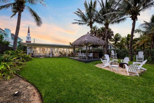 a resort yard with white chairs and palm trees at Oceanfront Cocoa Beach Vacation Home Private Beach, Tiki Bar & Family Fun in Cocoa Beach