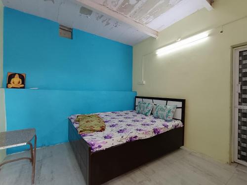 a bedroom with a bed with a blue wall at Rajal Homestay in Dholovira