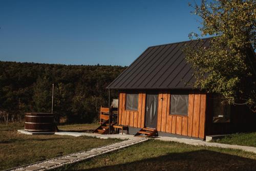 a small cabin with a black roof at Beneháti kunyhók in Matrafured