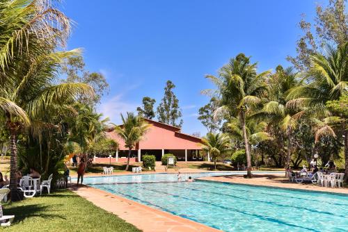 a swimming pool in front of a resort with palm trees at Hotel Fazenda Bonjuá in Montes Claros