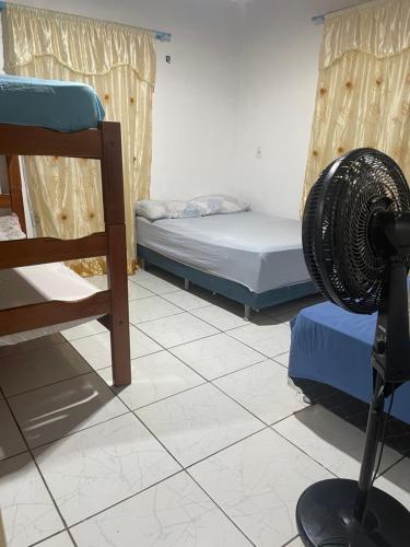 a room with two beds and a fan on the floor at Hostel Carol in Boa Vista