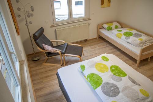 Cette petite chambre comprend deux lits et une chaise. dans l'établissement Ferienwohnung Bauernhaus, à Balingen