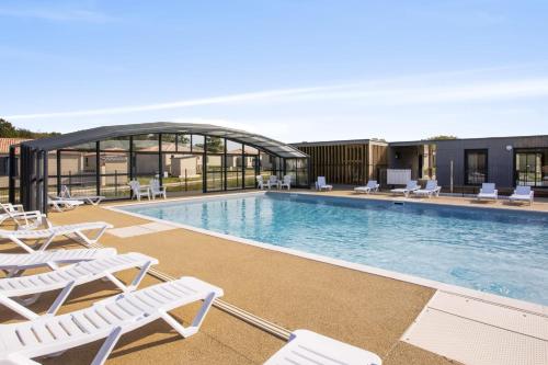 a swimming pool with white lounge chairs next to a building at Le Chalet Sessanta - Welkeys in Saubrigues