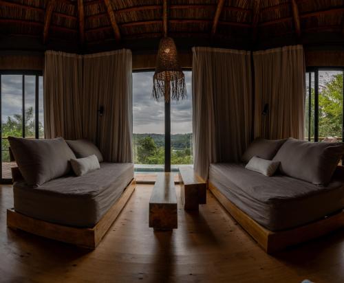 a living room with two beds and a large window at Reserva Natural Iguazú - Pristine Luxury Camp in Puerto Libertad