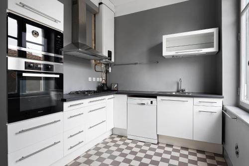 - une cuisine avec des placards blancs et du carrelage noir et blanc dans l'établissement CentreVille T3 Cosy French Style, à Carcassonne