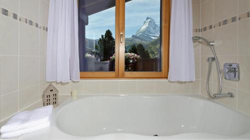 a bathroom with a tub and a window with a mountain at Chalet Michelangelo in Zermatt