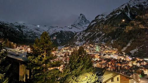 a view of a city at night with a mountain at Chalet Michelangelo in Zermatt