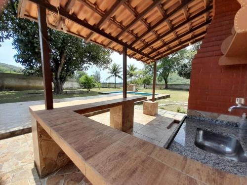 een houten picknicktafel onder een paviljoen bij Sítio Vivendo & Aprendendo in Tanguá