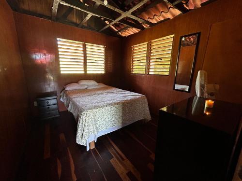 a bedroom with a bed and a dresser and windows at Cabaña a la orilla de la laguna in Bacalar