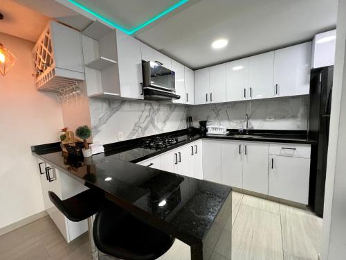een keuken met witte kasten en een zwart aanrecht bij Apartamento nuevo en Barranquilla in Barranquilla