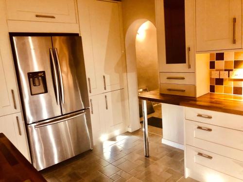 a kitchen with a stainless steel refrigerator and white cabinets at Chessington Blue with parking in Chessington