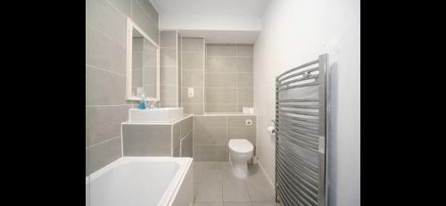 a bathroom with a tub and a toilet and a sink at Chessington Blue with parking in Chessington