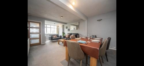 a dining room with a table and a living room at Chessington Blue with parking in Chessington