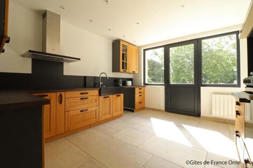 eine Küche mit Holzschränken und einem großen Fenster in der Unterkunft Gîte de Bel Oeuvre 