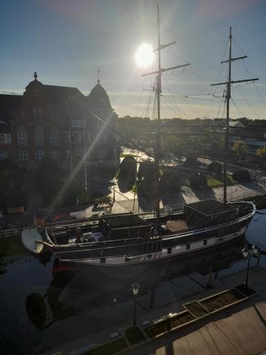 a boat docked in a marina with the sun behind it at Arkadenhaus - Hotel Freiherr von Schwarzenberg in Papenburg