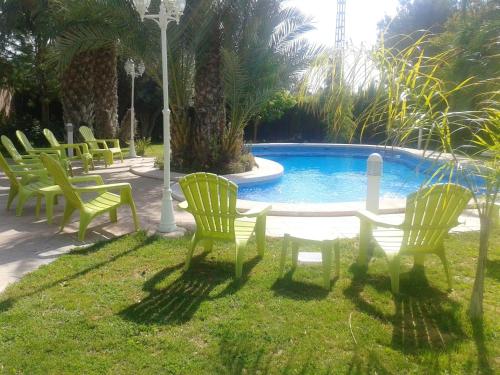 un grupo de sillas y una mesa frente a una piscina en 2 bedrooms house with shared pool furnished terrace and wifi at Elx 6 km away from the beach, en Torrellano