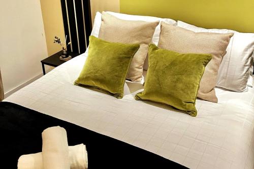 Una cama blanca con almohadas verdes. en Garden Eleven - Duplex City Centre Apartment en Hemel Hempstead