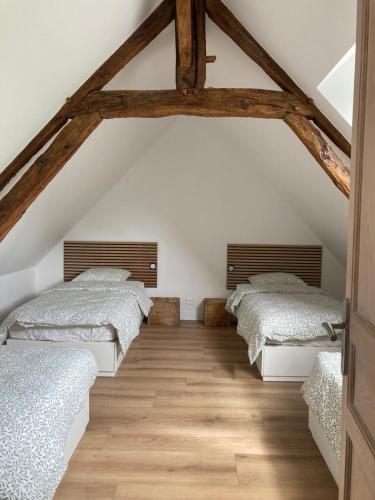 a attic bedroom with three beds and wooden floors at Gîte de Bel Oeuvre in Moulins-sur-Orne
