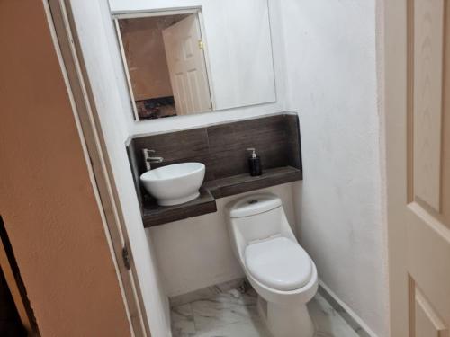 La salle de bains est pourvue de toilettes, d'un lavabo et d'un miroir. dans l'établissement Depa para 2 personas con aire acondicionado, à Manzanillo