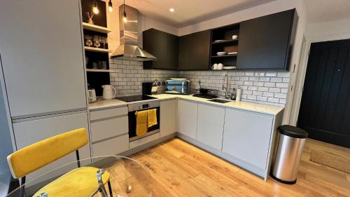 a kitchen with white cabinets and a yellow chair at Modern & stylish 1 bedroom flat in London